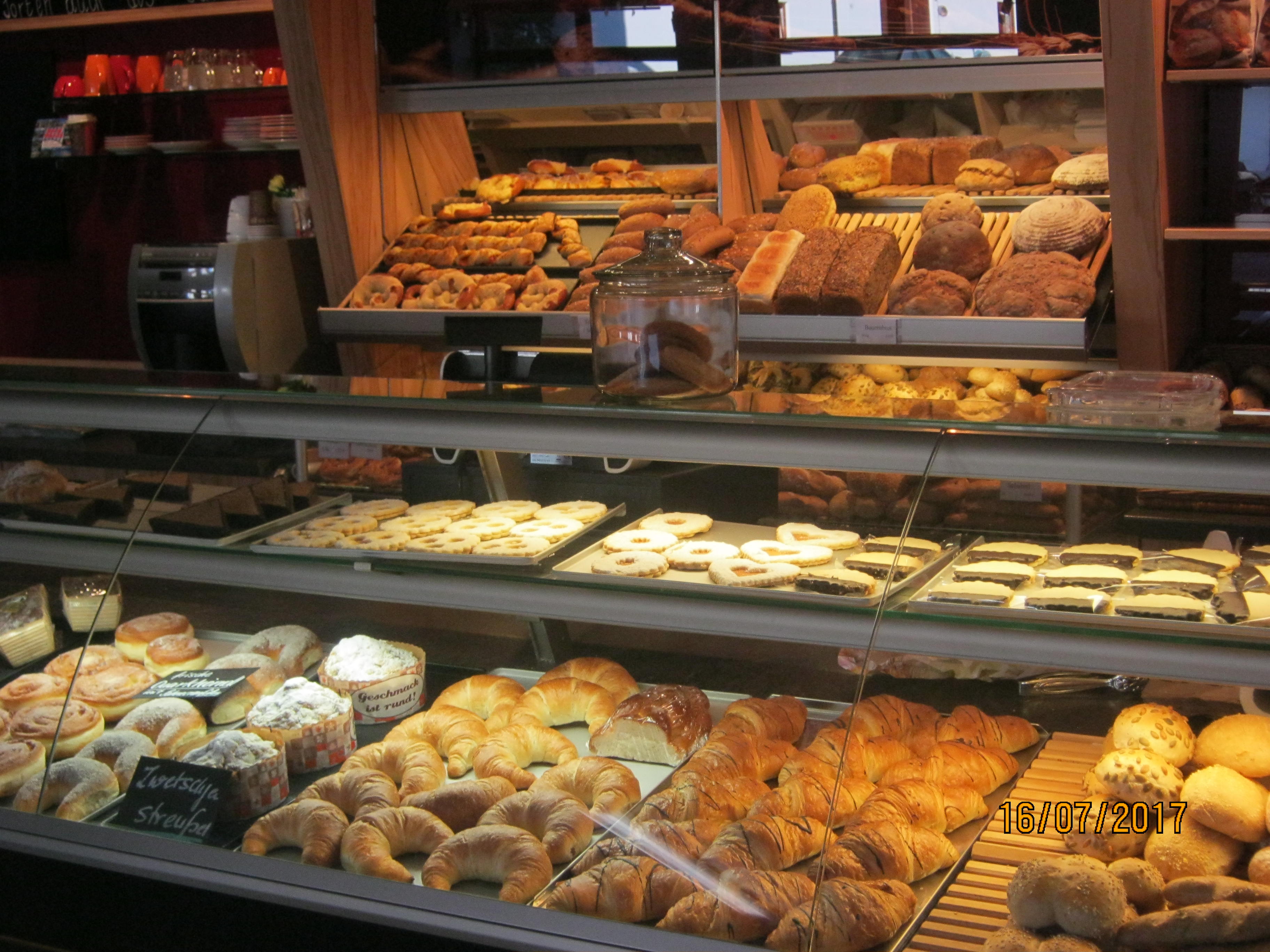 Auslage der Bäckerei mit Plunder, Croissants, Krapfen, Semmeln, Plätzchen und Broten im Hintergrund