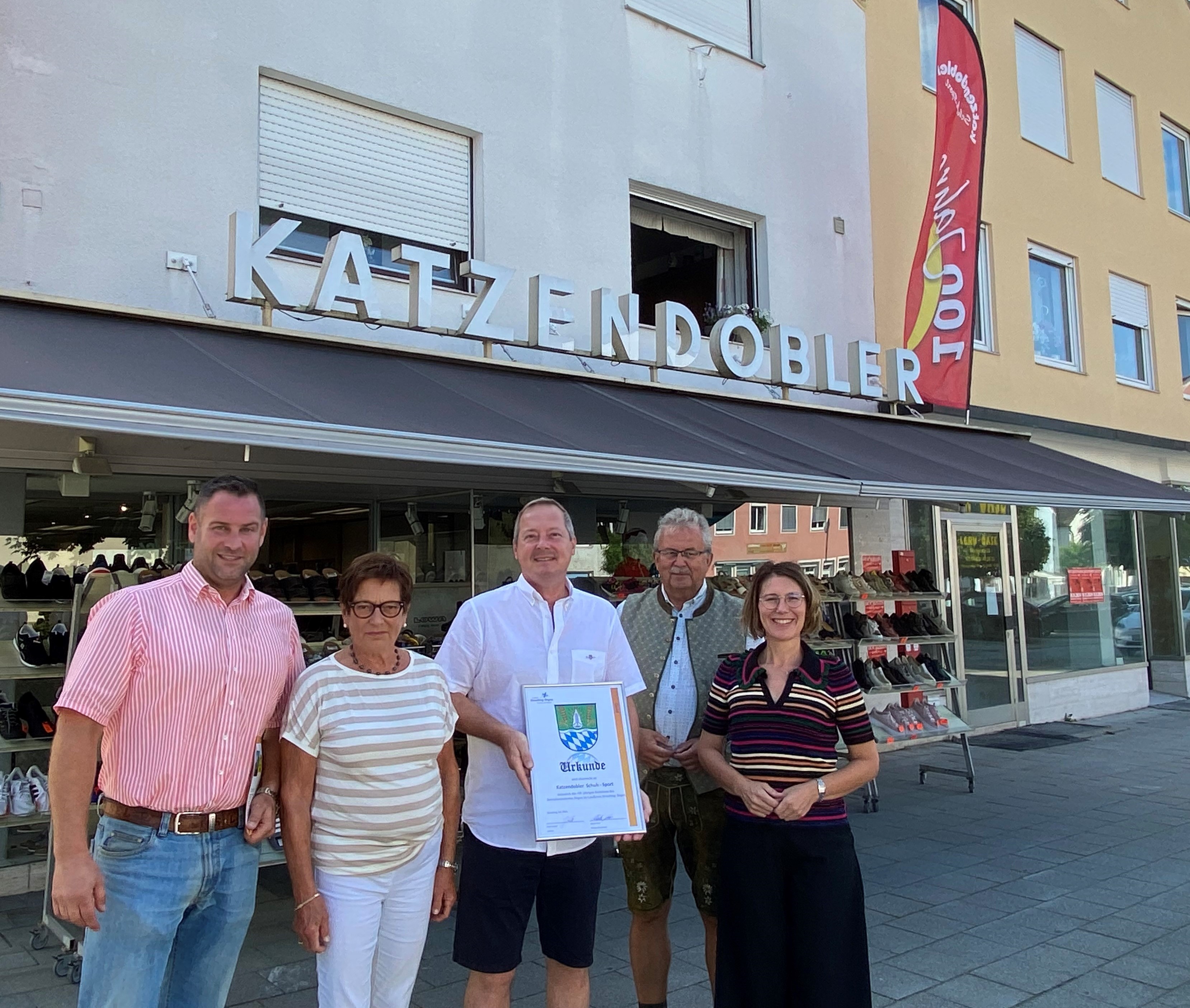 Martin Köck (Wirtschaftsreferent), Annemarie Katzendobler, Florian Katzendobler, Landrat Josef Laumer und Bürgermeisterin Andreas Probst stehen vor dem Geschäft am Bogener Stadtplatz.